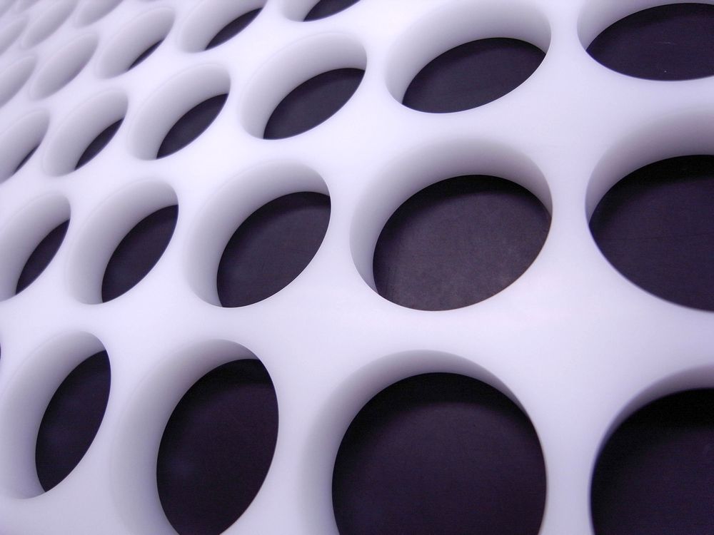 白ポリアセタール(POM)多穴プレート切削加工事例のアップ。φ45貫通穴周辺部を拡大し、面取り仕上げや切削面の状態が分かる写真。